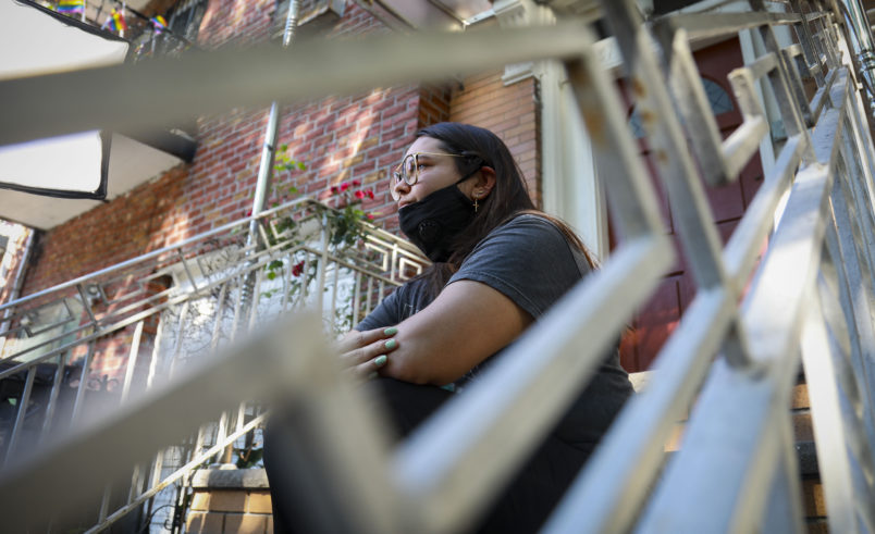Natalia Afonso, 27, an international student from Brazil at Brooklyn College, sit on a stoop outside her home during an interview, Thursday July 9, 2020, in New York.  Afonso, who is studying teaching education and finished her first semester this spring, said she has lived in the U.S. for 7 years and “I don’t see myself moving back to Brazil at this point.  (AP Photo/Bebeto Matthews)