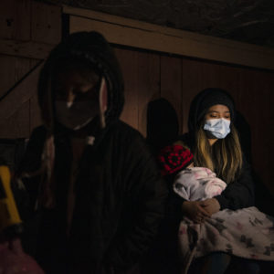 HOUSTON, TX - FEBRUARY 18: Surrounded by tarp and bedsheets, Evelyn Hernandez, 15, and her sister, Daeslyn Hernandez, 1, keep warm by the glow of a camping stove on their family’s front porch following an unprecedented winter storm in Houston, Texas on February 18, 2021. The Hernandez family lost power on Monday morning and are preparing for another deep freeze. (Photo by Callaghan O’Hare for The Washington Post)